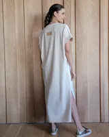 Vestido largo color crudo con cuello redondo y mangas cortas con ribete negro. Tiene corte recto y aberturas laterales en el ruedo.