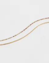Collar corto con doble cadena dorada de metal, una de ellas con strass de colores. Cierre de mosquetón.