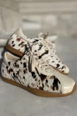 Zapatillas bajas con estampado animal print en blanco, marrón y negro, con puntera y talón en cuero color crema y suela de goma color caramelo.