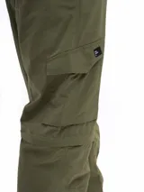 Pantalón de trekking convertible color verde militar, con piernas removibles mediante cierre a la altura de la rodilla, transformándolo en bermuda. Presenta múltiples bolsillos cargo con tapa y cierre, y cintura con pasadores para cinturón.