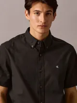 Camisa negra de manga corta, corte clásico, con cuello abotonado y logo de Calvin Klein bordado en el pecho.