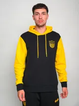 Hoodie negro con mangas amarillas y escudo bordado en el pecho.