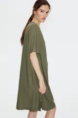 Vestido túnica a la rodilla en tejido liviano de viscosa color verde oliva con cuello mao y abertura en V. Modelo de corte holgado con hombros levemente caídos, mangas cortas y bajo recto con tajos laterales.