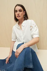 Camisa blanca de mangas cortas abullonadas con calados florales.