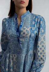 Vestido midi de corte amplio con estampado floral en tonos azules y blancos. Tiene cuello mao con botones y mangas largas abullonadas.
