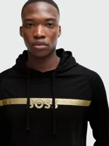 Sudadera negra con capucha de la marca Boss, con una franja horizontal dorada en el pecho y el logo de la marca en dorado.
