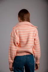 Sweater de punto color beige con rayas horizontales blancas, cuello polo con cierre de cremallera y mangas largas.