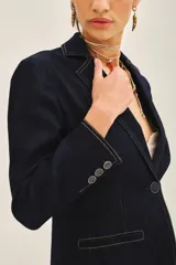 Blazer azul marino de denim con forro azul satinado, solapas de muesca, cierre frontal con un botón, bolsillos delanteros con solapa y puños con botones.