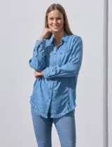 Camisa celeste de tencel con cuello con solapa, escote en V, abertura central con botones, bolsillo aplicado y ruedo desflecado.