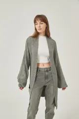 Saco largo de tejido de punto grueso color gris, con mangas largas y bolsillos frontales. Diseño holgado y sin cierre.