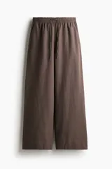 Pantalón marrón de lino, corte holgado, tiro alto, cintura elastizada con cordón ajustable, bolsillos laterales y pierna ancha.