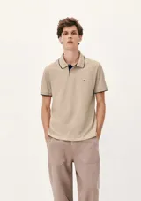 Camisa polo color rosa claro con cuello clásico, tapeta de dos botones y bordado de logo en el pecho. Presenta ribete azul marino en cuello y mangas. Corte clásico.