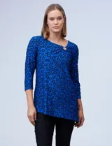 Blusa de tejido texturado color negro, con escote en V descentrado y aplique de aro metálico, terminación de ruedo asimétrico.