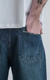 Pantalón de denim azul oscuro, corte wide leg y cinco bolsillos.