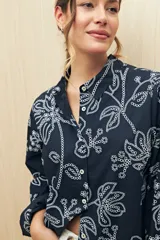 Camisa blanca de manga larga confeccionada en algodón liviano con calados florales. De corte clásico y botones frontales.