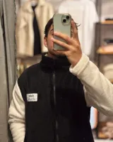 Campera de peluche negra con mangas blancas, cierre frontal y cuello alto.