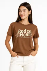 Remera negra de algodón con cuello redondo y estampado de estilo vintage con imágenes de carteles y textos relacionados con el mundo del rodeo.