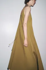Vestido midi color ocre de Zara Woman Collection, confeccionado en hilatura con mezcla de algodón. Presenta escote pico, tirantes finos y tejido con volumen.