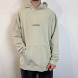 Canguro color gris claro con capucha y cordones ajustables. Estampado en la espalda con un esqueleto de pez, texto "Surf N' Destroy" y otros diseños gráficos.