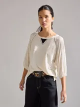 Remera color crudo de corte holgado, con cuello redondo y mangas 3/4 con puños elásticos.