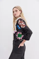Saco corto negro con bordado de lentejuelas con forma de flores de colores. Tiene cuello redondo y ganchos invisibles al frente.