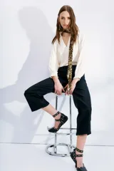 Pantalón jean negro de tiro alto, corte oxford y proceso de coating con acabado símil cuero. Pierna ancha desde la cadera a la pantorrilla.