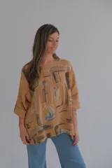 Blusa color ocre con estampado abstracto en tonos marrones y grises. Tiene cuello redondo y mangas 3/4 con botón.