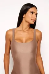 Jumpsuit corto color marrón, de calce ajustado, con escote cuadrado y espalda descubierta. Confeccionado en tejido elástico acanalado con efecto brillante.