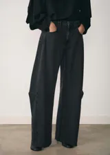 Pantalón de jean negro de corte wide leg, tiro bajo y bajo deshilachado. Cuenta con cierre de cremallera y botón, trabillas, cinco bolsillos y costuras decorativas.
