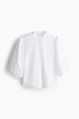 Blusa blanca de algodón con cuello mao y botones. Manga abullonada al codo con broderie tono sobre tono y puños festoneados.