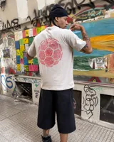 Remera color crema de corte clásico con cuello redondo y estampado en la espalda de una huella digital con forma de pelota de fútbol y el logo de Umbro.