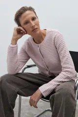 Chaqueta de tejido de punto color celeste pálido, con cuello redondo y cierre frontal de botones metálicos. Presenta un tejido texturizado con franjas horizontales en relieve y mangas largas.