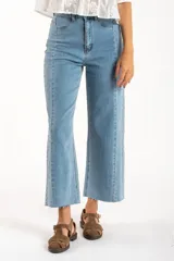 Jean de mezclilla azul claro, tiro medio, corte recto con leve campana al tobillo. Presenta costuras verticales marcadas en el frente y en los laterales de las piernas, y terminación deshilachada en el ruedo.