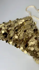 Top dorado con lentejuelas, estilo halter, con tiras regulables en cuello y espalda.