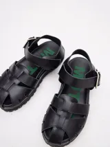 Sandalias romanas color verde oliva, con tiras entrecruzadas y hebilla lateral. Suela de goma negra con plataforma de 3cm. Fabricadas en cuero vacuno.