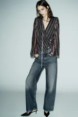 Body negro con escote en V cruzado, mangas largas acampanadas y apliques de lentejuelas.