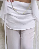 Pantalón blanco de gasa con cintura elastizada y cierre lateral. Incluye pollera superpuesta.