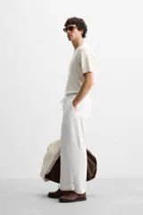 Pantalón de jogging color beige confeccionado en tejido de mezcla de algodón. Cuenta con cintura elástica ajustable con cordón, bolsillos frontales y traseros.