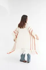 Ruana artesanal color crudo con rayas horizontales color ladrillo y flecos.