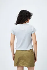 Remera color beige de punto acanalado con silueta relajada y manga corta raglán. El ruedo tiene terminación ondulada. El tejido con elasticidad ligera brinda comodidad y movimiento.