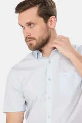 Camisa celeste lisa de manga corta, confeccionada en algodón, con cuello clásico, cierre frontal con botones y bolsillo en el pecho.