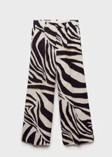 Pantalón de mujer con estampado de cebra en tonos blanco, negro y dorado. Diseño wide leg, tiro medio y detalle de pinzas. Cierre delantero con botón, gancho y cremallera ocultos.