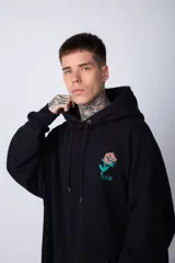 Buzo canguro negro de algodón friza, corte oversize y estampado de una rosa roja en el pecho.
