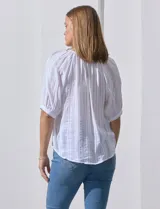 Blusa blanca de algodón marca Zac & Rachel, con cuello a la base, escote en V, abertura central con botones y sisa con aplique calado.