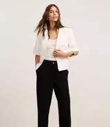 Pantalón zanahoria de poliéster color marrón, de cintura alta, con cierre tradicional, bolsillos traseros y botón metalizado con efecto martillado.