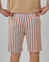 Bermuda de lino a rayas verticales color naranja, azul y blanco, con bolsillos traseros ribeteados.