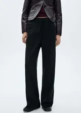 Pantalón negro de tejido fluido con caña ancha, diseño drapeado, goma elástica en la cintura y corte recto.