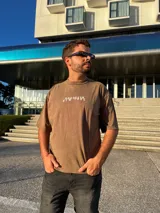 Remera marrón con estampado blanco con la palabra "Brooklyn" en el frente.