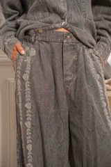 Pantalón denim gris con efecto lavado y detalles de pedrería en el frente, de corte amplio.