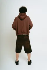 Bermuda de jean color marrón con lavado gastado, corte baggy, bolsillos grandes y bordados ornamentales en los laterales.